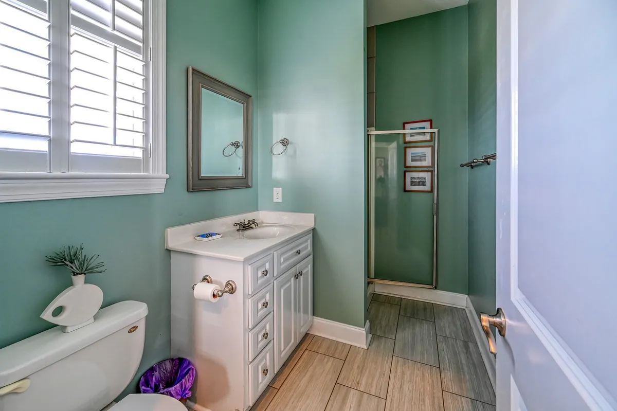 A modern bathroom with a vanity sink, shower area, framed mirror, and toilet. The mood is soothing and convenient—ideal for private routines and comfort.