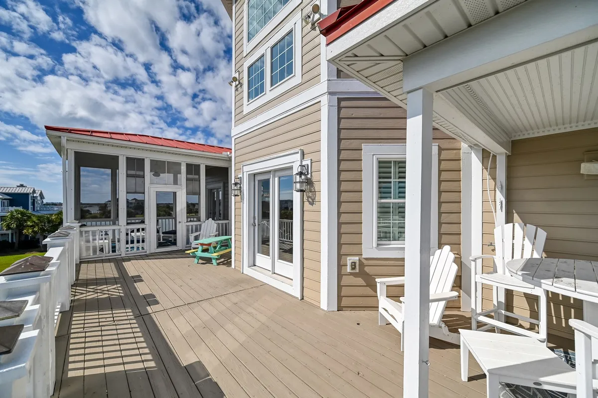 A welcoming deck furnished with adirondack chairs, looking out over surrounding greenery and providing a glimpse of the home's exterior spaces. The inviting setup suggests a place to relax after a day at the beach or host casual gatherings with friends and family.