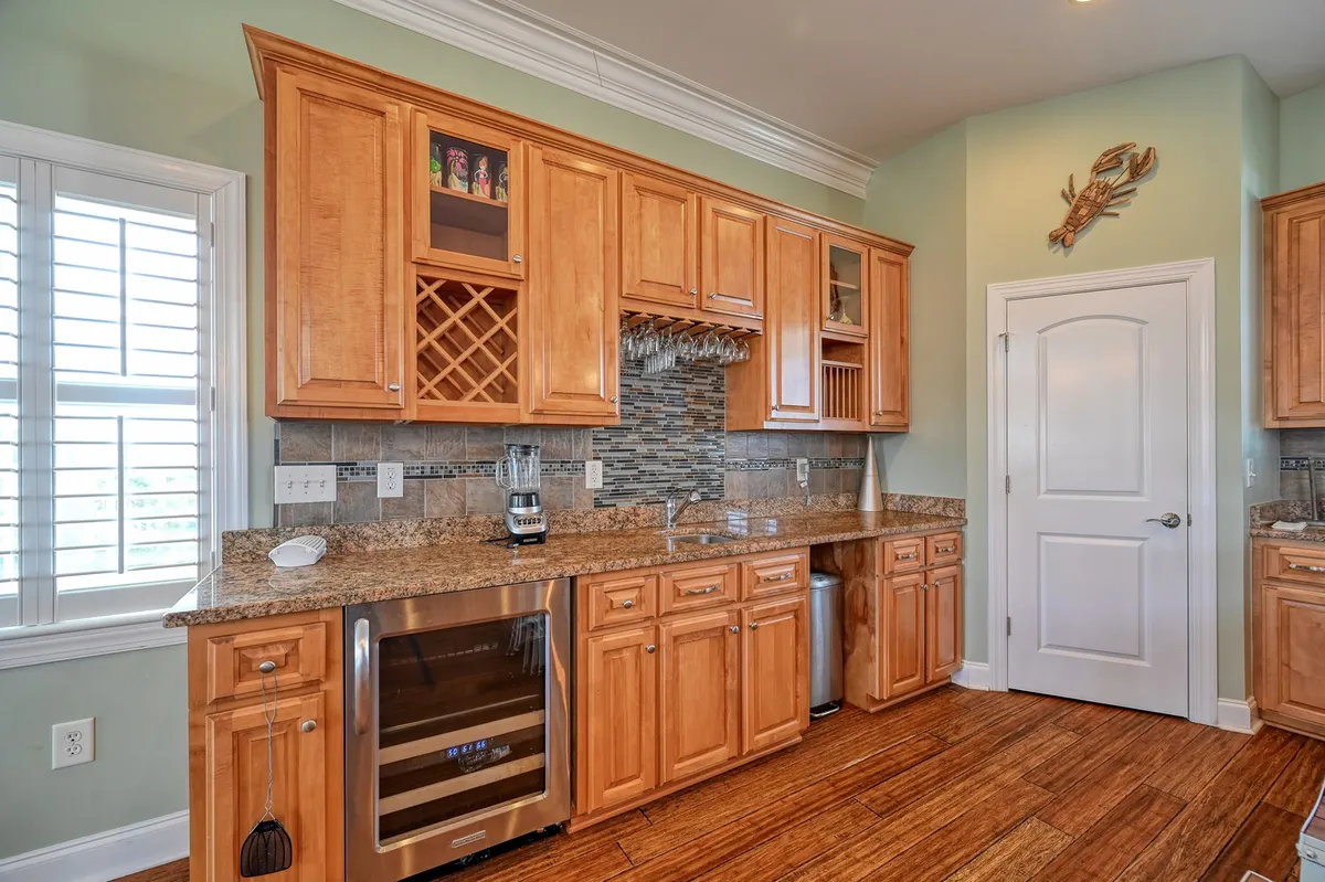 A modern kitchen featuring expansive granite countertops, warm wooden cabinets, a built-in wine rack, stainless steel appliances, and a dishwasher. The space is designed for both functionality and social cooking experiences, ideal for group cooking or hosting.