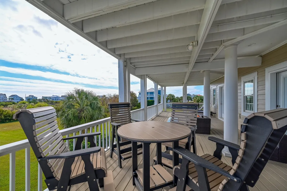 An exterior patio with a circular table and comfortable chairs offers a panoramic view of the surrounding landscape. The scene feels tranquil and spacious, inviting guests to relax and connect with nature or each other.