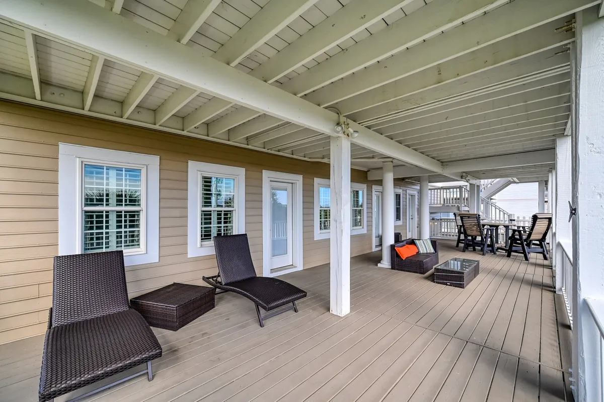 A cozy outdoor seating area featuring loungers and a glass-topped table, surrounded by greenery. The space is designed for relaxation, socializing, and enjoying the outdoors, evoking the feel of a community amenity area.